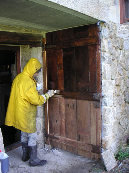 Rosa pintando la puerta restaurada (también por ella), ya en su nuevo sitio por debajo de la escalera hacia la moreira, con aceite de linaza: